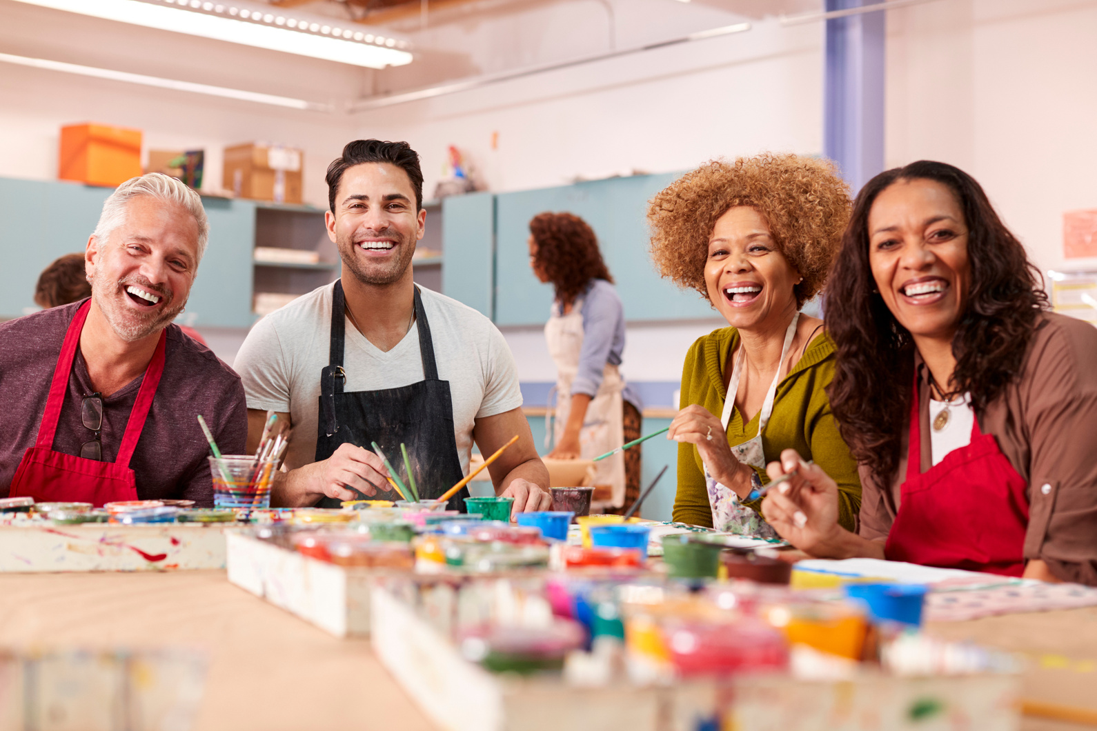 a group of people sitting at a table with paintbrushes in front of them